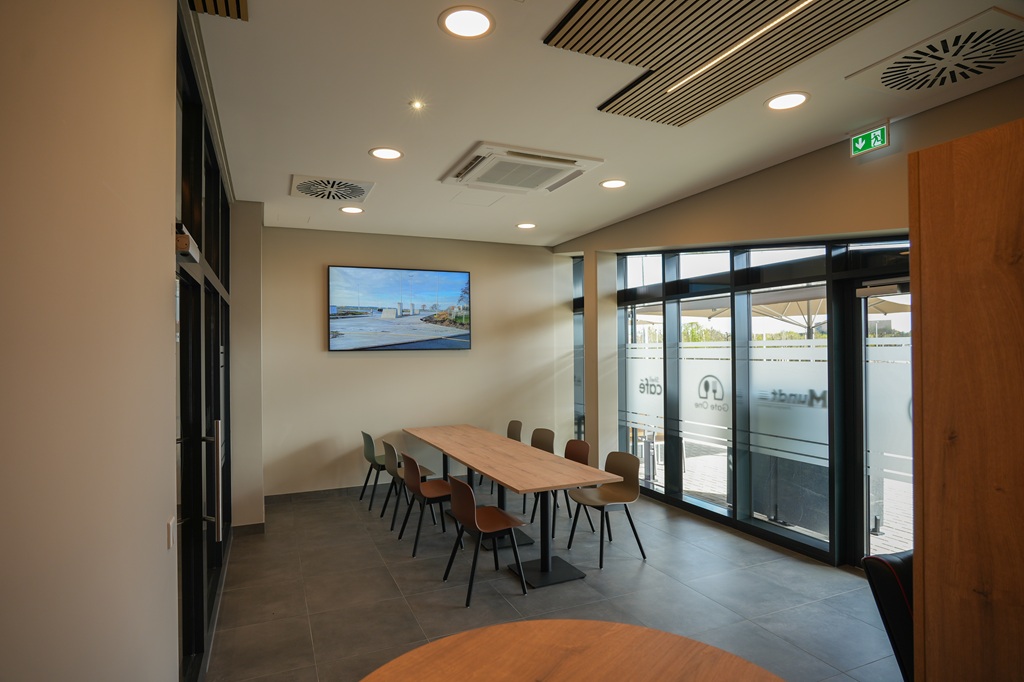 Moderner Meetingraum mit Naturlicht und Tischgruppe Eleganter Raum mit Glasfront, ideal für Gespräche oder kleine Arbeitsgruppen in entspannter Umgebung.