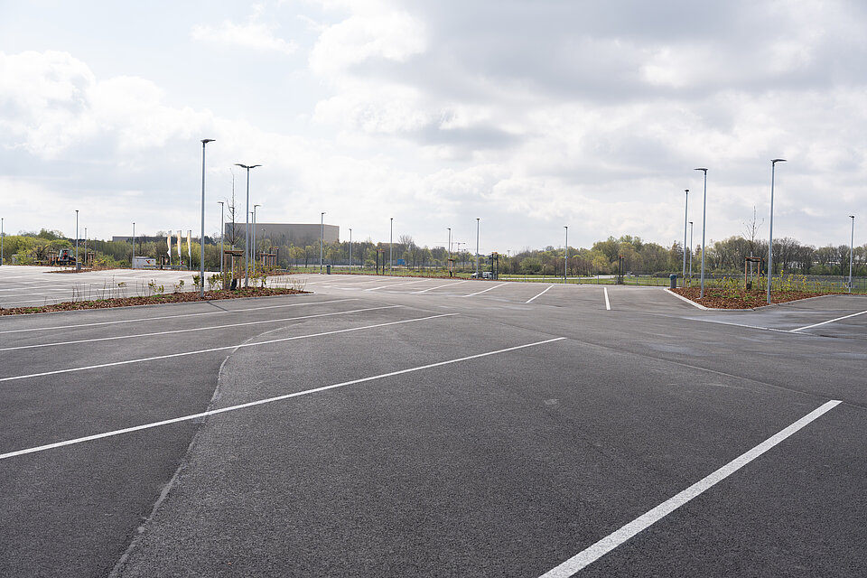 117 LKW-Parkplätze unter strahlendem Himmel, großzügig angelegt und von Grünpflanzen umgeben.