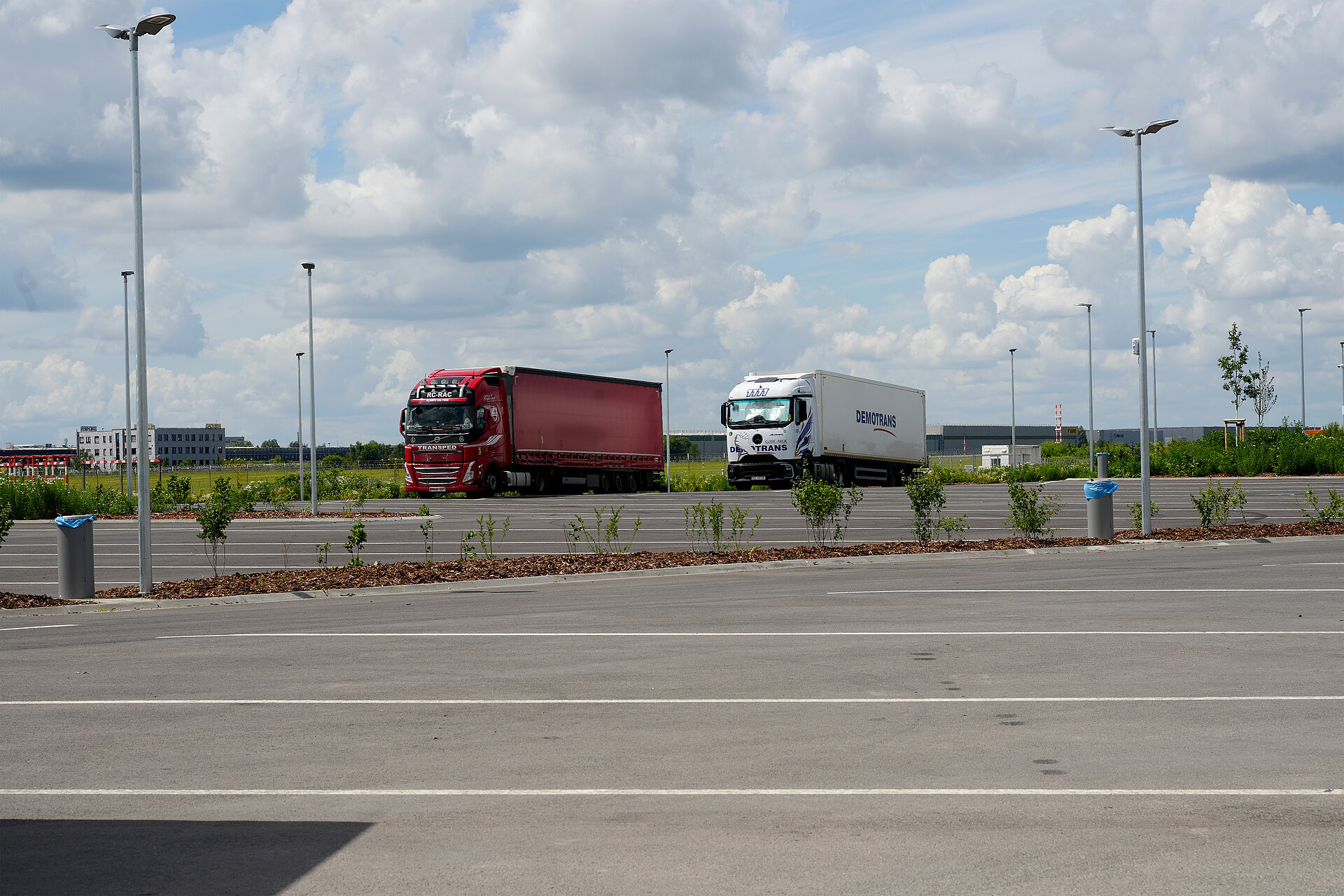 Blick auf einen sauberen, großzügigen Parkplatz mit LKW's und freien Stellplätzen.
