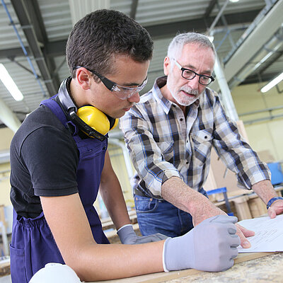 Handwerker und Vorabeiter stehen am Tisch und besprechen sich