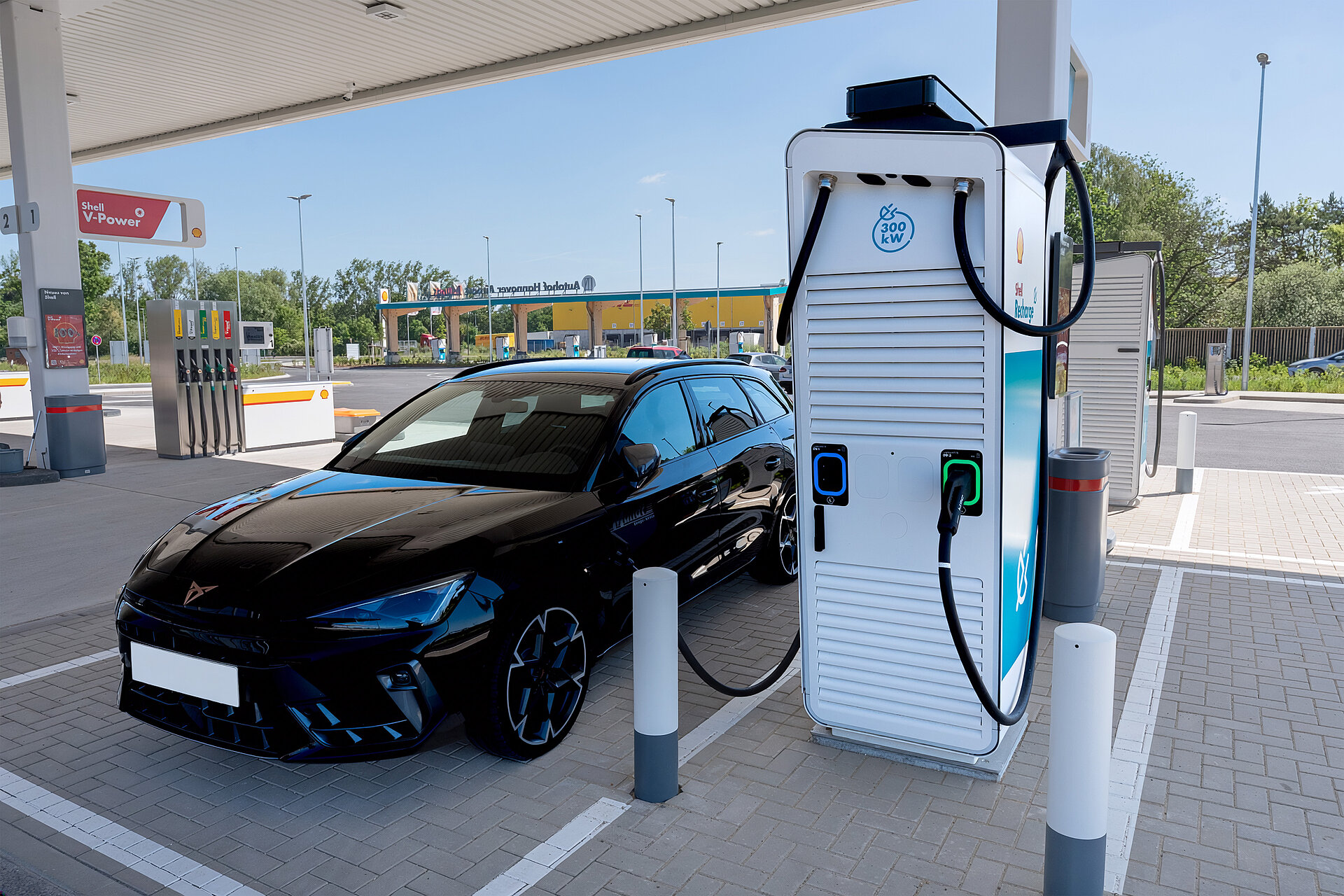 EIn schwarzes Auto steht an einer Shell Recharge Ladesäule