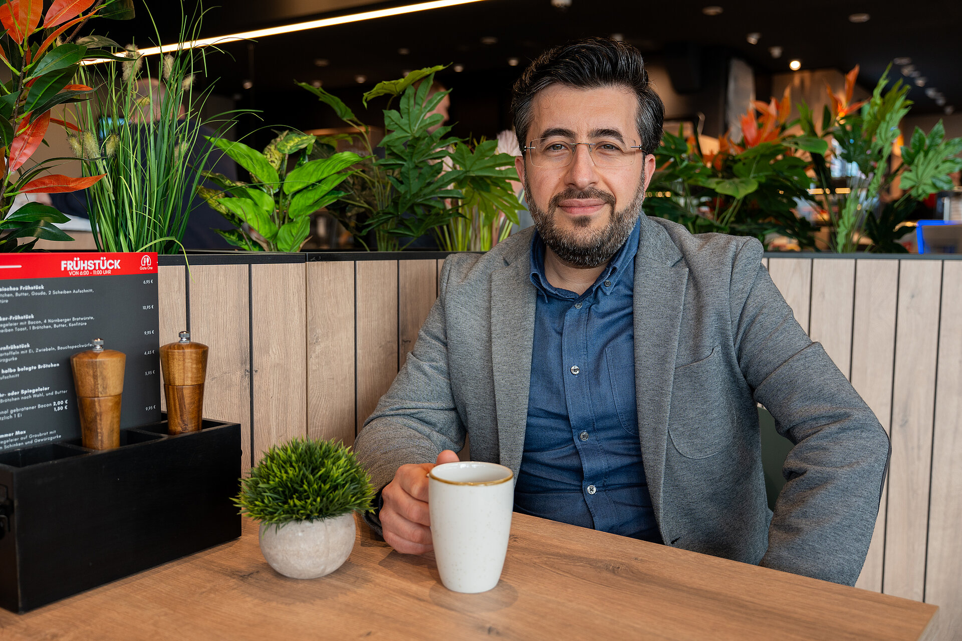 Ein Mann sitzt im Gastraum des Gate One mit einer Tasse Kaffee am Tisch