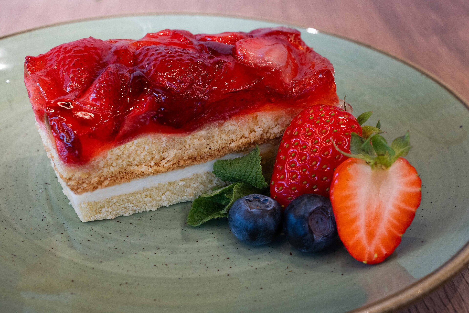 Ein frischer Erdbeerkuchen auf einem Teller, dekoriert mit Erdbeeren und Heidelbeeren