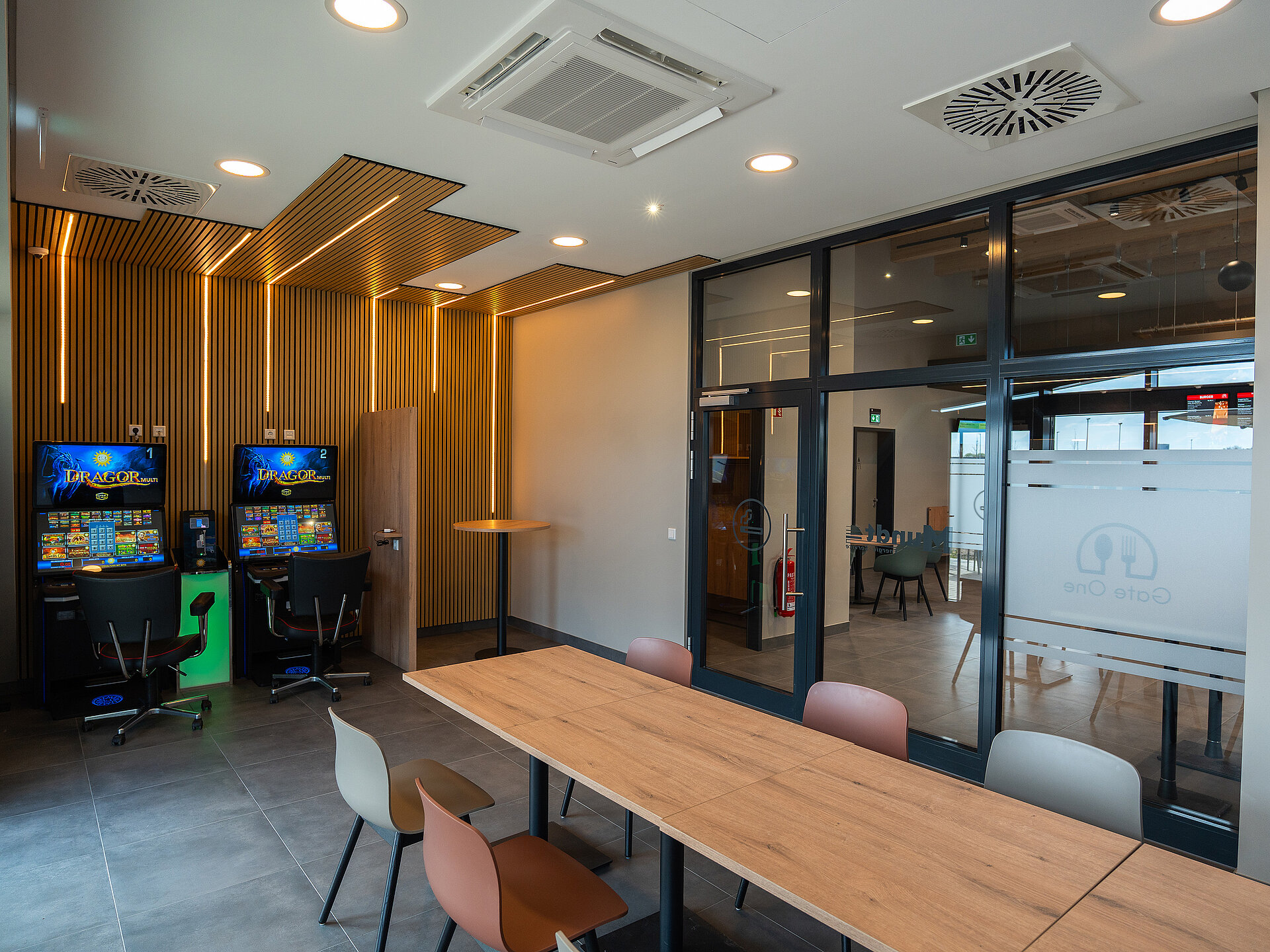 Blick in die moderne Trucker Lounge. Ausgestattet mit zwei Spielautomaten, Acoustikpaneelen mit LED Streifen und einem großen Tisch mit vielen Sitzplätzen.