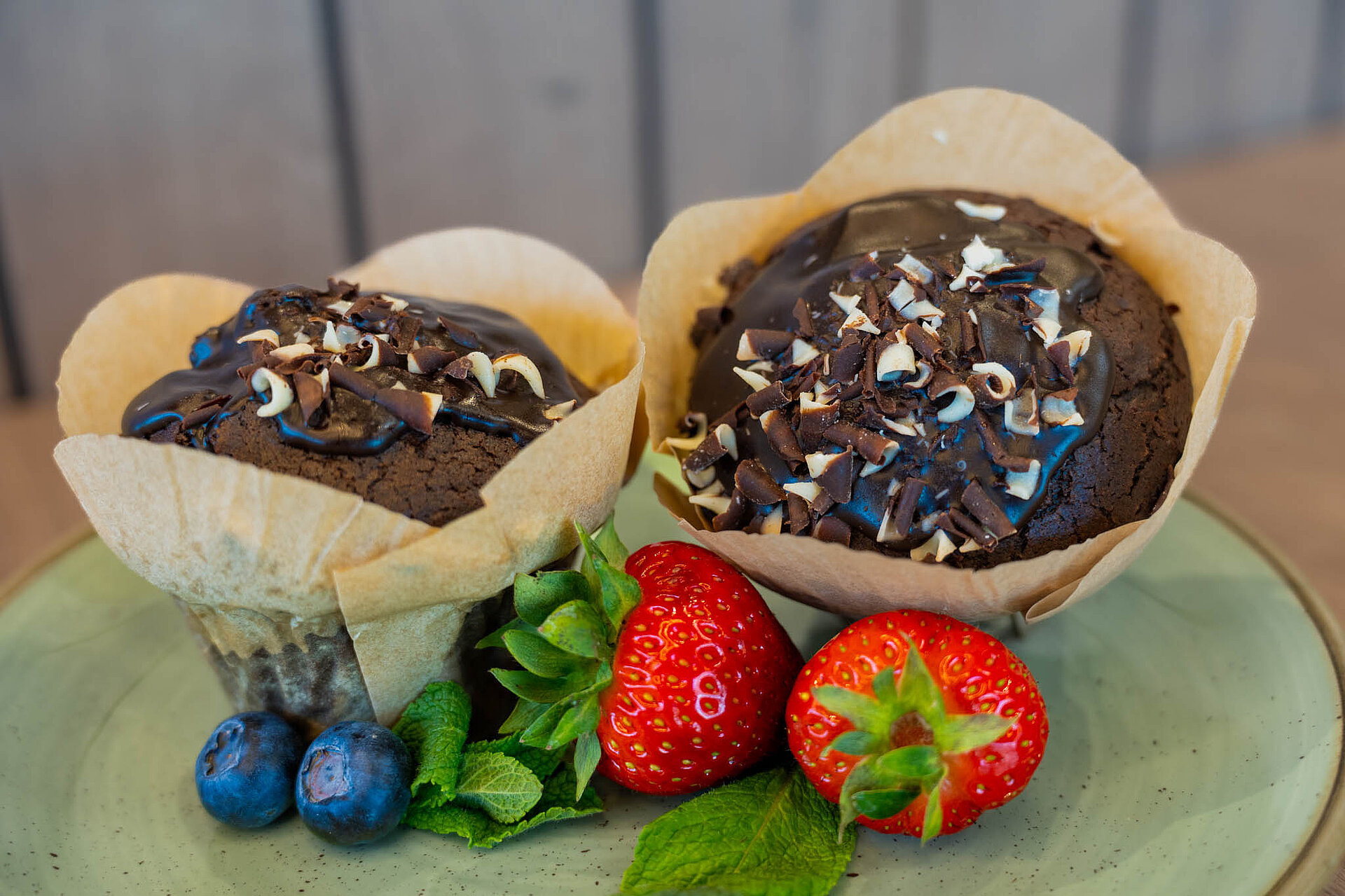 Zwei Schokoladen Muffins mit Erdbeeren und Heidelbeeren